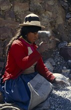 BOLIVIA, Chukiuta, Woman knelling on a Banco Minero de Bolivia sack breaking rocks into small