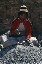 BOLIVIA, Chukiuta, Woman sitting in a Banco Minero de Bolivia sack breaking rocks into small pieces