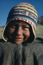 BOLIVIA, , Head and shoulders portrait of a Bolivian boy smiling wearing a colourful wool chullo