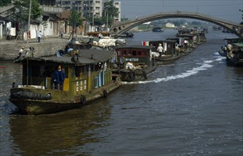 CHINA, Jiangsu Province, Transport, Barge train travelling down the Grand Canal under bridge