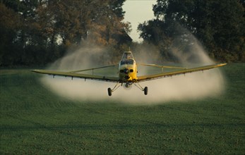 ENGLAND, West Sussex, Slinfold, Yellow plane crop spraying