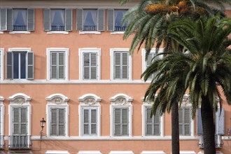 ITALY, Lazio, Rome, Palm trees in front of a pink building with pale blue shuttered windows in