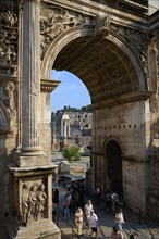 ITALY, Lazio, Rome, Tourists walking through the triumphal Arch of Septimius Severus with the three