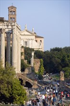 ITALY, Lazio, Rome, Tourists walking past the Temple of Antoninus and Faustina in the Forum with