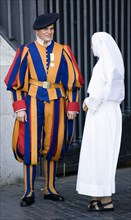 ITALY, Lazio, Rome, Vatican City A Swiss Guard in full ceremonial uniform dress talking to a nun
