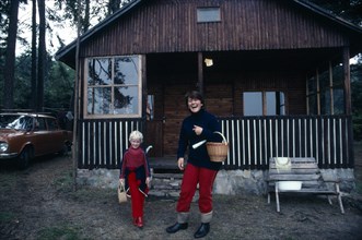 CZECH REPUBLIC, Housing, Rural home with young woman and child standing outside.