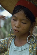 MALAYSIA, Borneo, Sarawak, Young Kayan woman harvesting dry hill rice wearing heavy earrings
