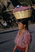 GUATEMALA, Lake Atitlan, Indian girl walking along road carrying a basket of washing on top of her