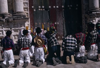 GUATEMALA, El Quiche, San Andres de Sajcabaja, Quiche Indian men kneeling in prayer outside the