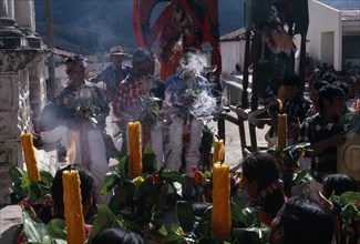 GUATEMALA, El Quiche, San Andres de Sajcabaja, Quiche Indian women holding candles facing Confradia
