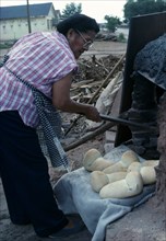 USA, New Mexico, Zuni, "Zuni  Native American Indian woman making bread in a Horno mud adobe
