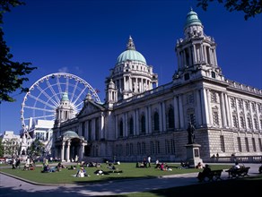 IRELAND, North, Belfast, People sitting or lying in the sun in the grounds of City Hall with The