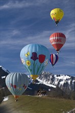 SWITZERLAND, Canton de Vaud, Chateau d'Oex, Hot Air Balloons in flight with mountain backdrop and