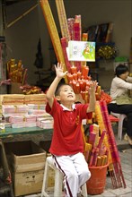 CHINA, Sichuan Province, Chongqing, Boy incense seller throws his book up in glee outside the Arhat