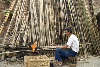 CHINA, Sichuan Province, Chongqing, Man strengthening bamboo joints with fire