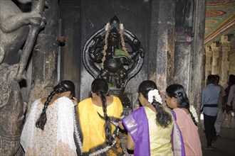 INDIA, Tamil Nadu, Madurai, Female worshippers praying in front of a Ganesh shrine Meenakshi Temple
