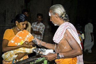 INDIA, Tamil Nadu, Madurai, Brahmin blessing a baby held in his mothers arms at Meenakshi Temple