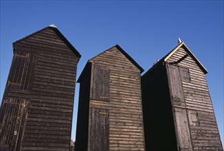 ENGLAND, East Sussex, Hastings, The Net Shops. Tall black wooden huts used for storing fishing nets