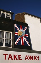 ENGLAND, East Sussex, Hastings, Neptune Fish and Chip Shop Take Away sign with Union Jack flag.