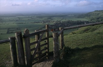 ENGLAND, West Sussex, Devils Dyke, Stile gate on Devil’s Dyke with view over lush green South Downs