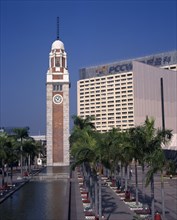CHINA, Hong Kong, Kowloon, Kowloon Star ferry clock tower at end of rectangular pool lined by palms