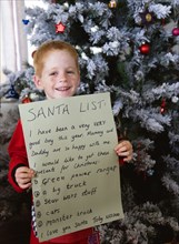 RELIGION, Festivals, Christmas, Young smiling red headed boy standing in front of a decorated