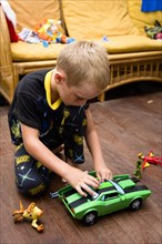 RELIGION, Festivals, Christmas, Young boy in his pyjamas playing on the floor with his green toy