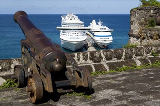 WEST INDIES, Grenada, St George, An old canon pointing out to sea at Fort George with two cruise