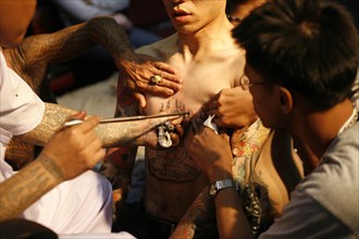 THAILAND, Phuket, Man having tattoo applied to torso.