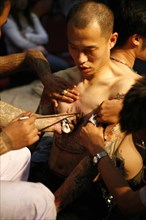THAILAND, Phuket, Man having tattoo applied to torso.