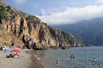 FRANCE, Corsica, Golfe Di Porto, "Plage De Bussaglia, sandy beach with sunbathers & umbrellas.