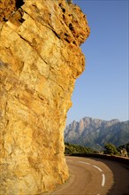 FRANCE, Corsica, Golfe De Porto, "Golden rock face with coastal road, near Porto"