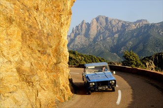 FRANCE, Corsica, Golfe De Porto, "Golden rock face with coastal road & car, near Porto"