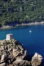 FRANCE, Corsica, Golfe Di Porto, "Porto, Genoese tower on rocky headland with blue waters & boats"