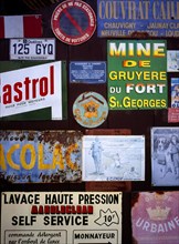 FRANCE, Indre et Loire, Chinon, A collection of enamelled advertising signs seen on a garage door.
