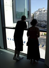ENGLAND, East Sussex, Eastbourne, Young silhouetted couple looking out the window of the Towner