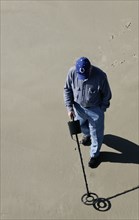 USA, Georgia, Tybee Island, Man using a metal detector on the beach.