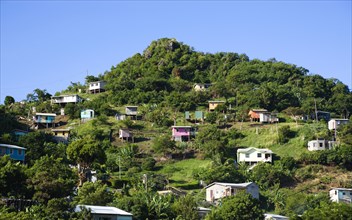 WEST INDIES, Grenada, St George, Houses built on stilts lining a hillside.