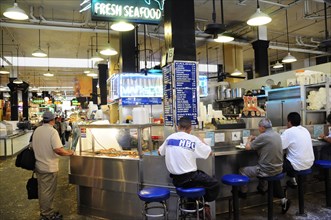 USA, California, Los Angeles, Central Market scene with people sat around a seafood bar.