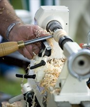 ENGLAND, West Sussex, Findon, Findon village Sheep Fair Man using a wood lathe with a chisel