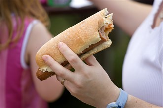 ENGLAND, West Sussex, Findon, Findon village Sheep Fair Teenage girl holding a hot dog with tomato