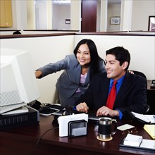 BUSINESS, Offices, Computers, Businessman and a businesswoman working on a desktop PC in an office.