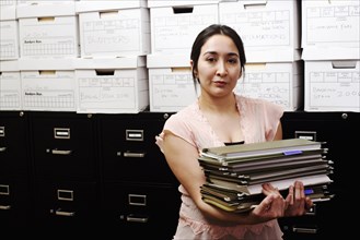 BUSINESS, Offices, Paperwork, Portrait of a file clerk holding a stack of files in front of a