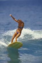 SPORT, Sea, Surfing, "Woman surfer wearing bikini, riding small wave with both arms raised to aid