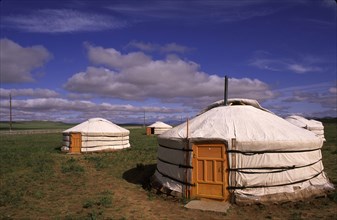 MONGOLIA, Nomads, Traditional ger huts on grassland area with dramatic cloudscape above.