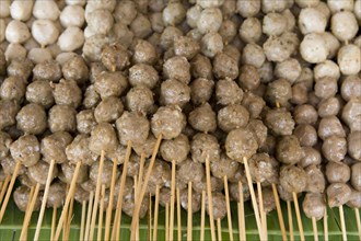THAILAND, North, Chiang Mai, Close up of pork meat balls on wooden skewers in the market.
