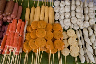 THAILAND, North, Chiang Mai, Close up of a selection of food on wooden skewers in the market.