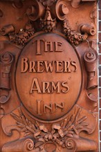 ENGLAND, East Sussex, Lewes, "High Street, Brewers Inn terracotta sign on pub wall."
