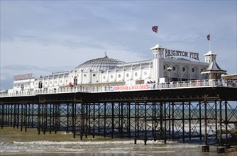 ENGLAND, East Sussex, Brighton, The Pier at low tide with people walking on the pier.
