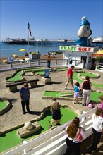 ENGLAND, East Sussex, Brighton, Adults and children playing miniature golf on a Crazy Golf course